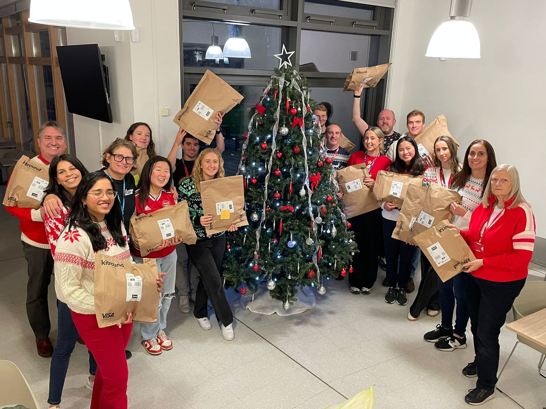 Volleyball England staff celebrating around a Christmas tree with festive jumpers and donation bags for kitround