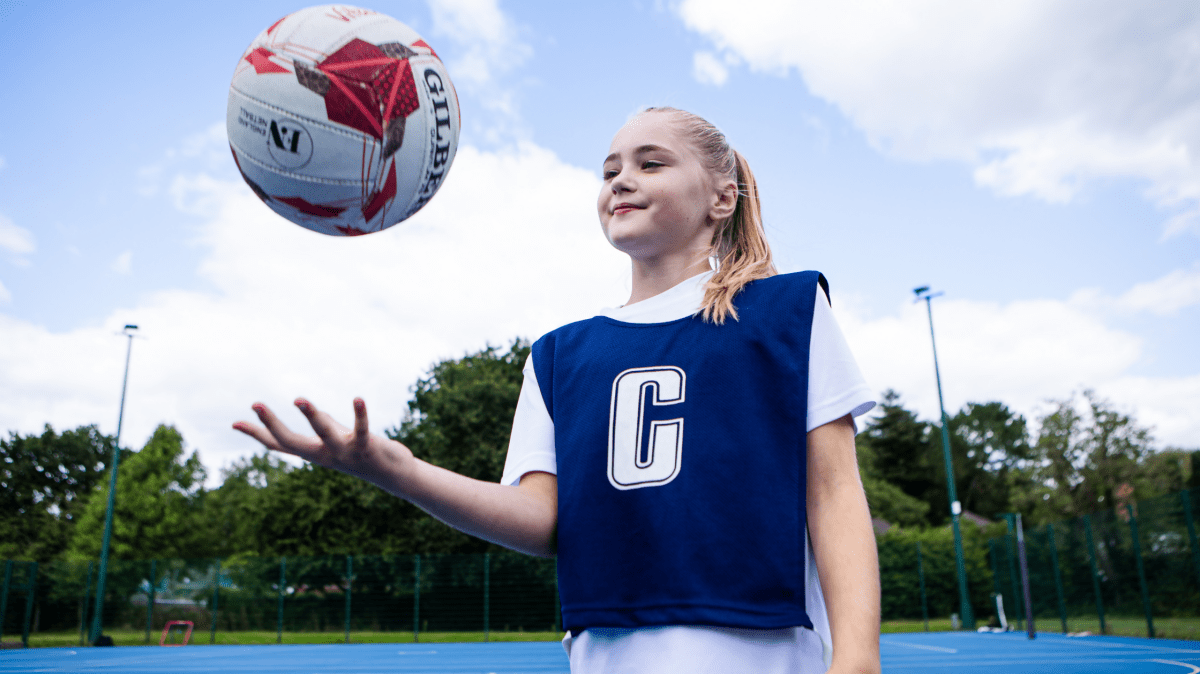 A teenage girl playing netball outdoors