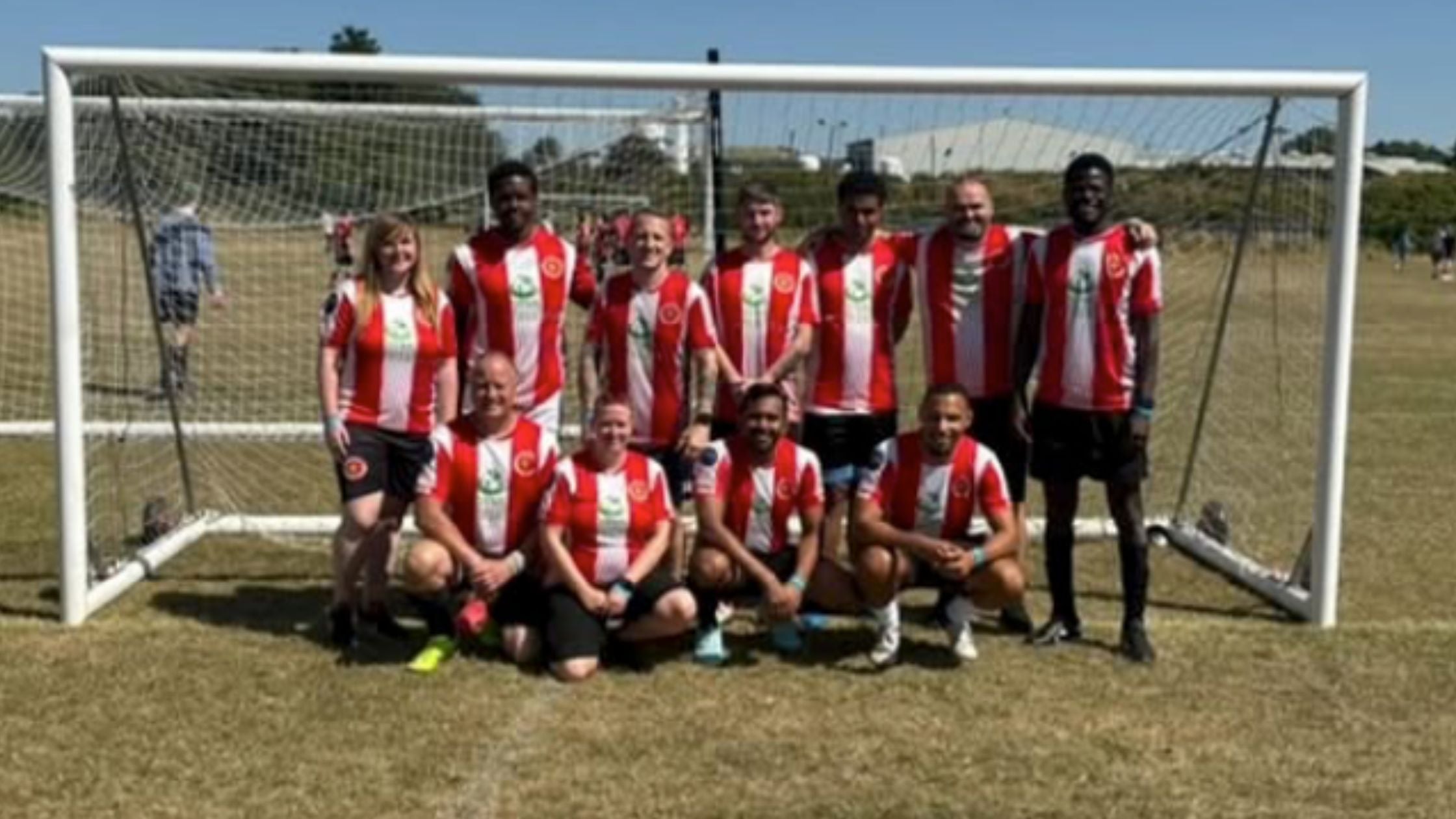 Soccer team posing in front of a goalpost on a field