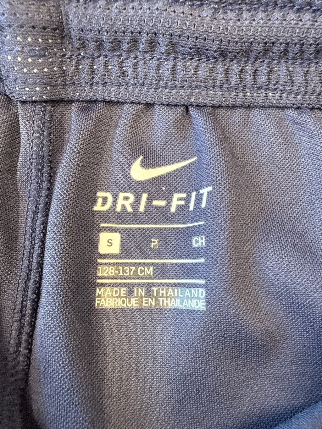 Nike Dri-FIT label and size markings inside navy kids' football shorts