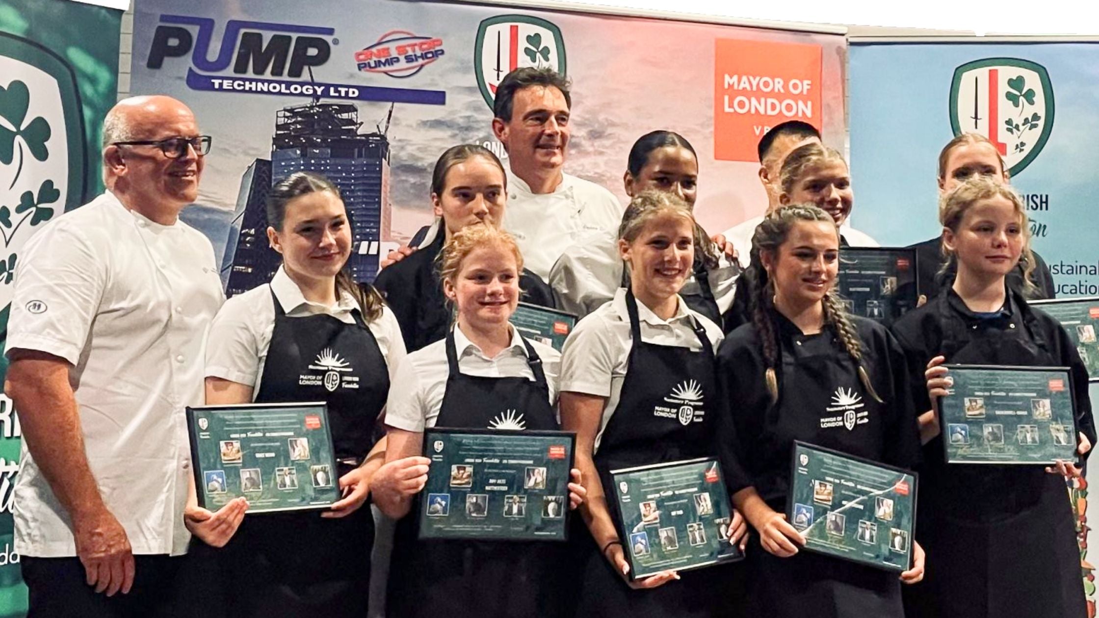 Group of people, likely chefs, holding awards in front of a promotional backdrop with logos.