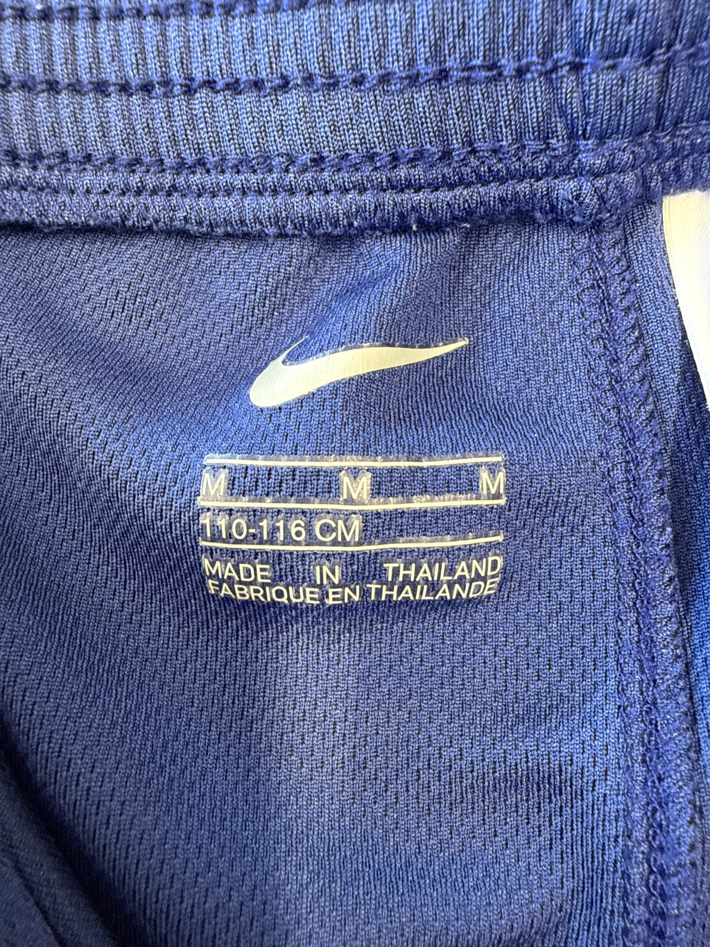 Close-up of size tag inside Barcelona Nike football shorts showing medium size and 110-116 cm