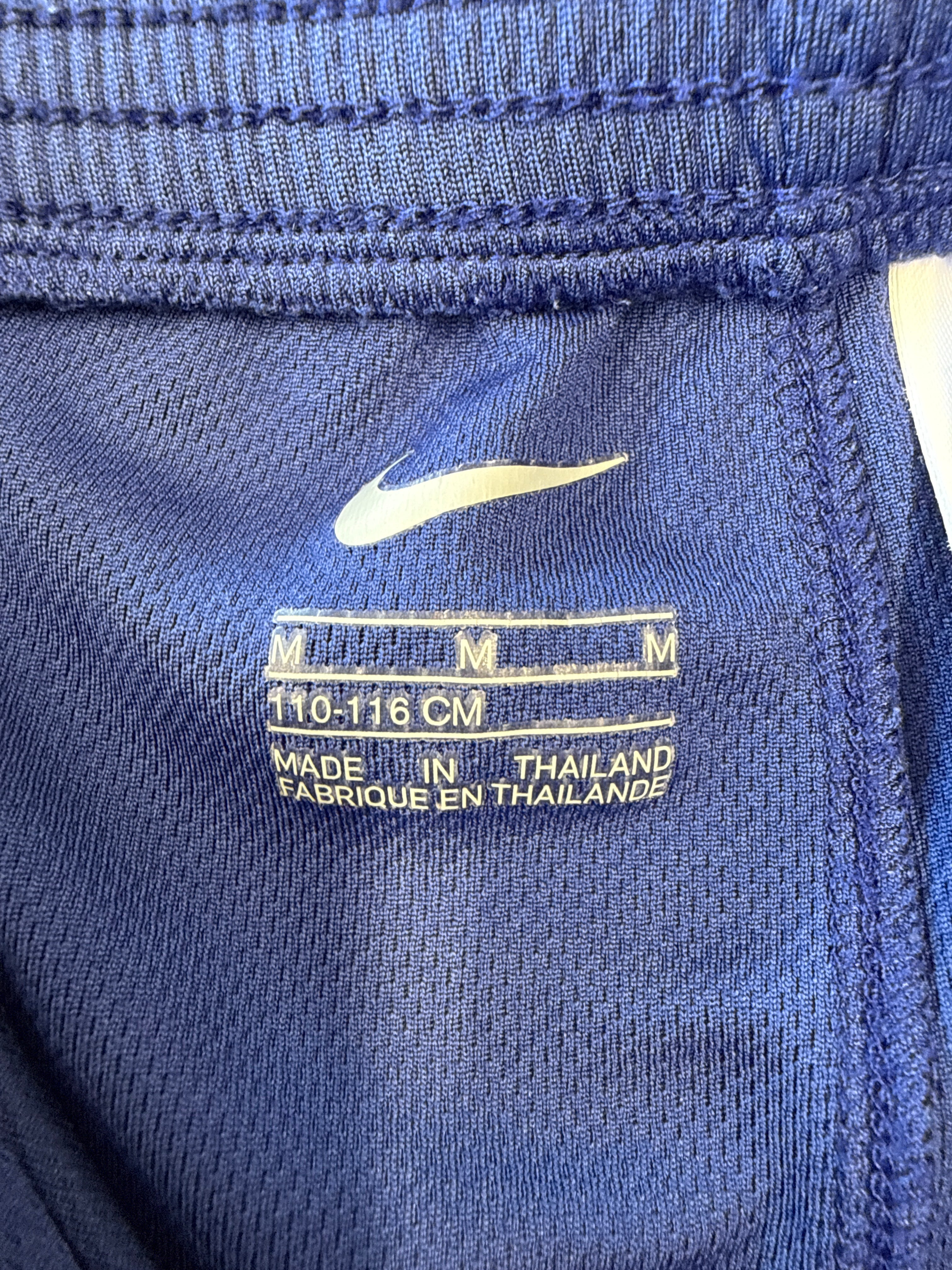 Close-up of size tag inside Barcelona Nike football shorts showing medium size and 110-116 cm