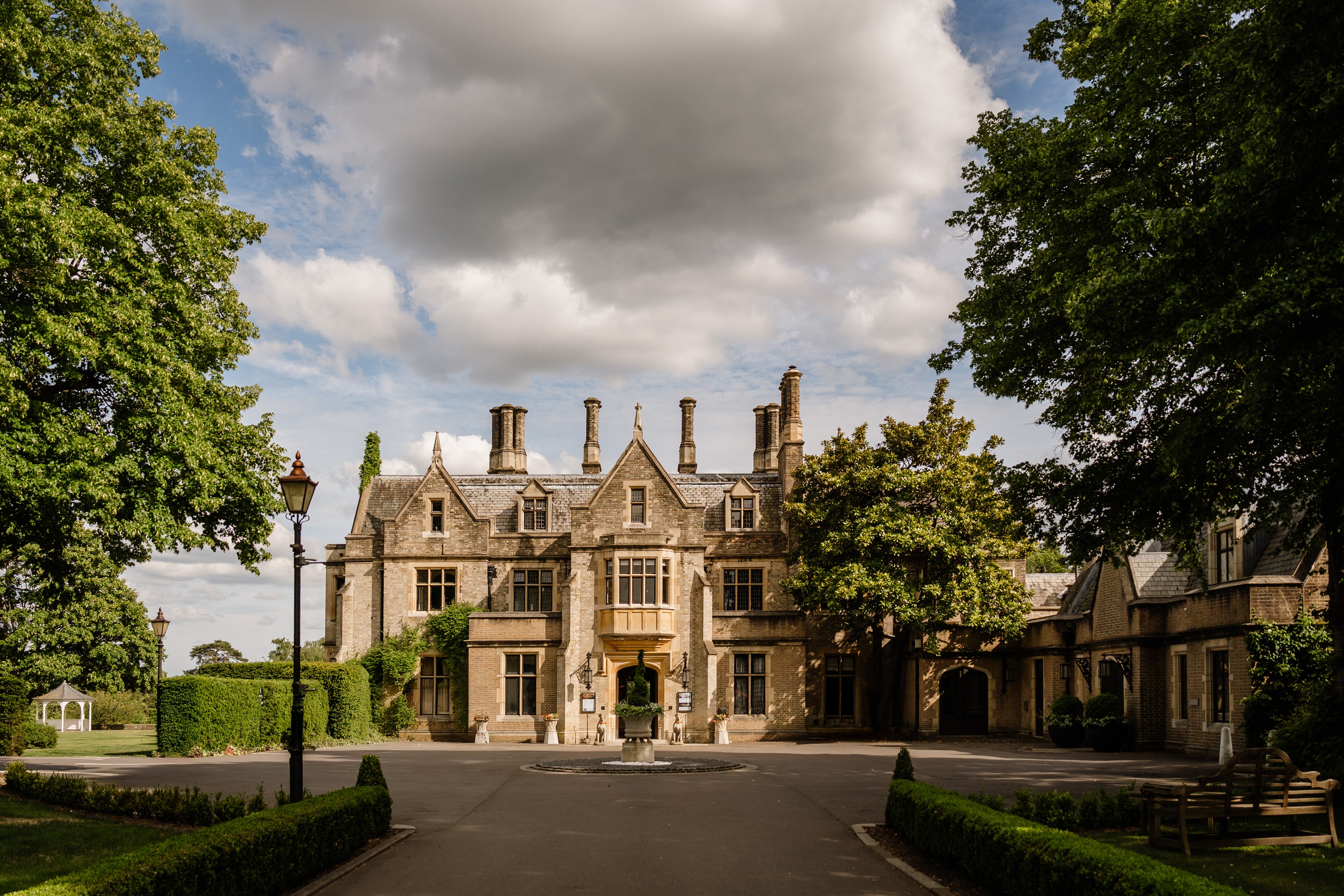 Large manor house with a driveway and trees on a cloudy day