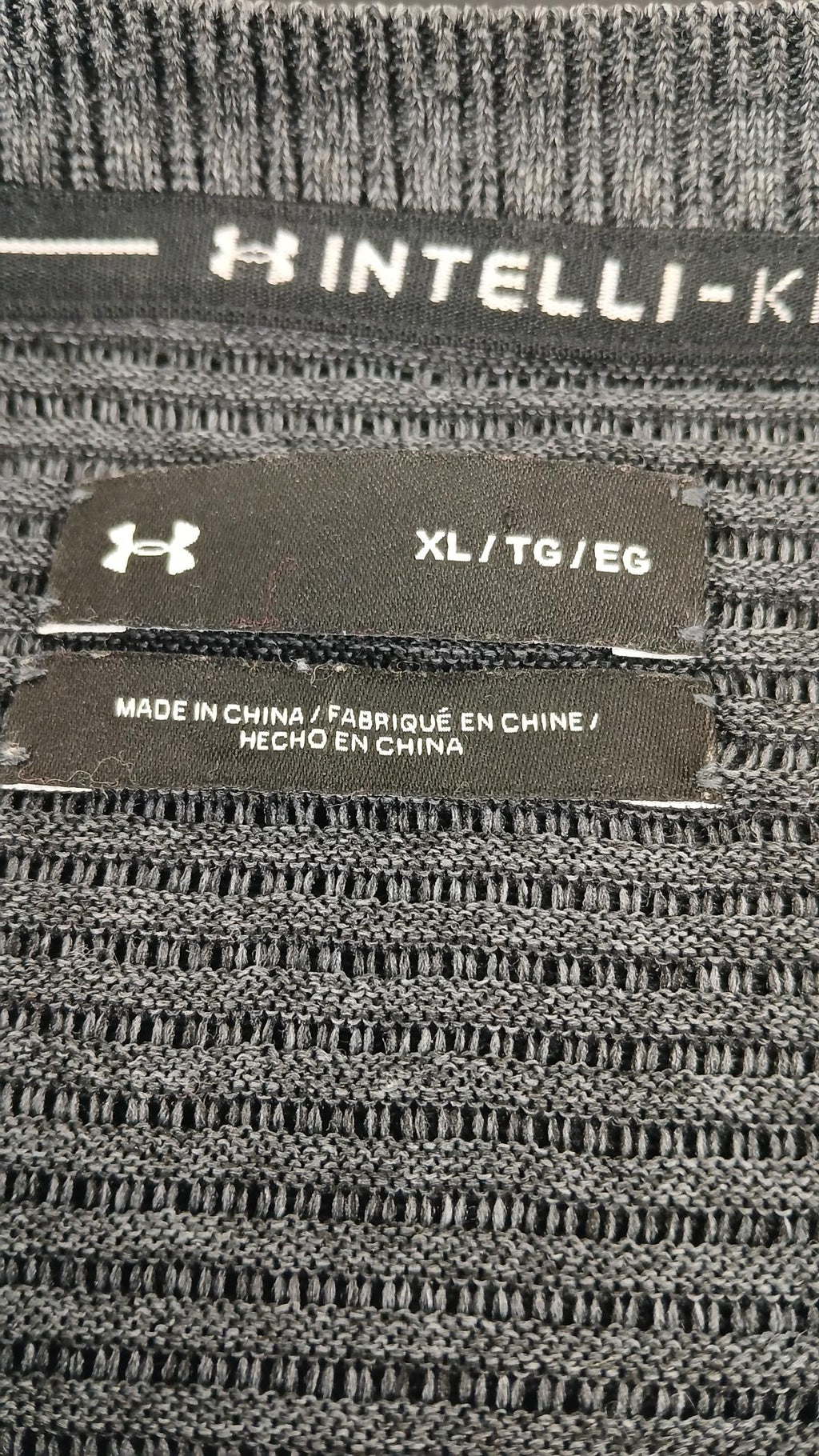 Close-up of Under Armour jumper label showing size XL and intelli-knit fabric detail