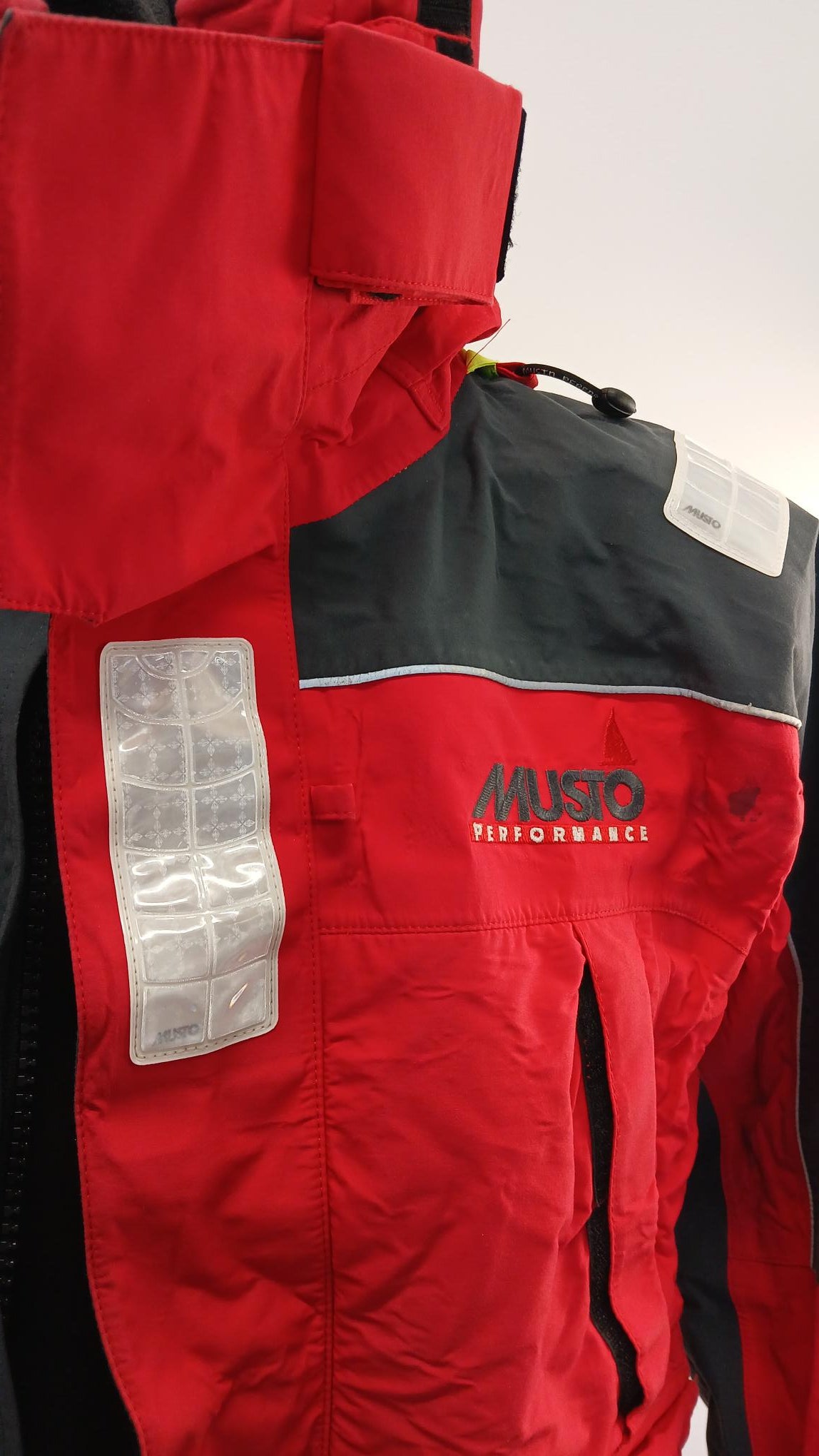 Detailed shot of reflective strips and Velcro fastenings on red and dark grey sailing jacket