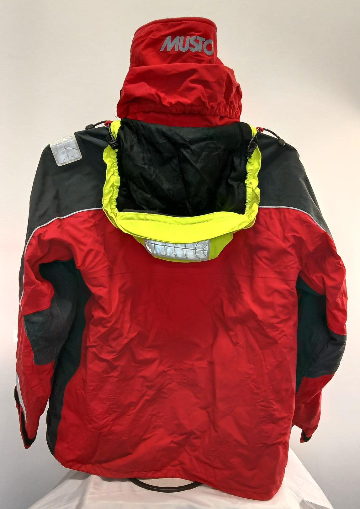 Back view of Musto sailing jacket showing hood with adjustable drawcord and reflective details