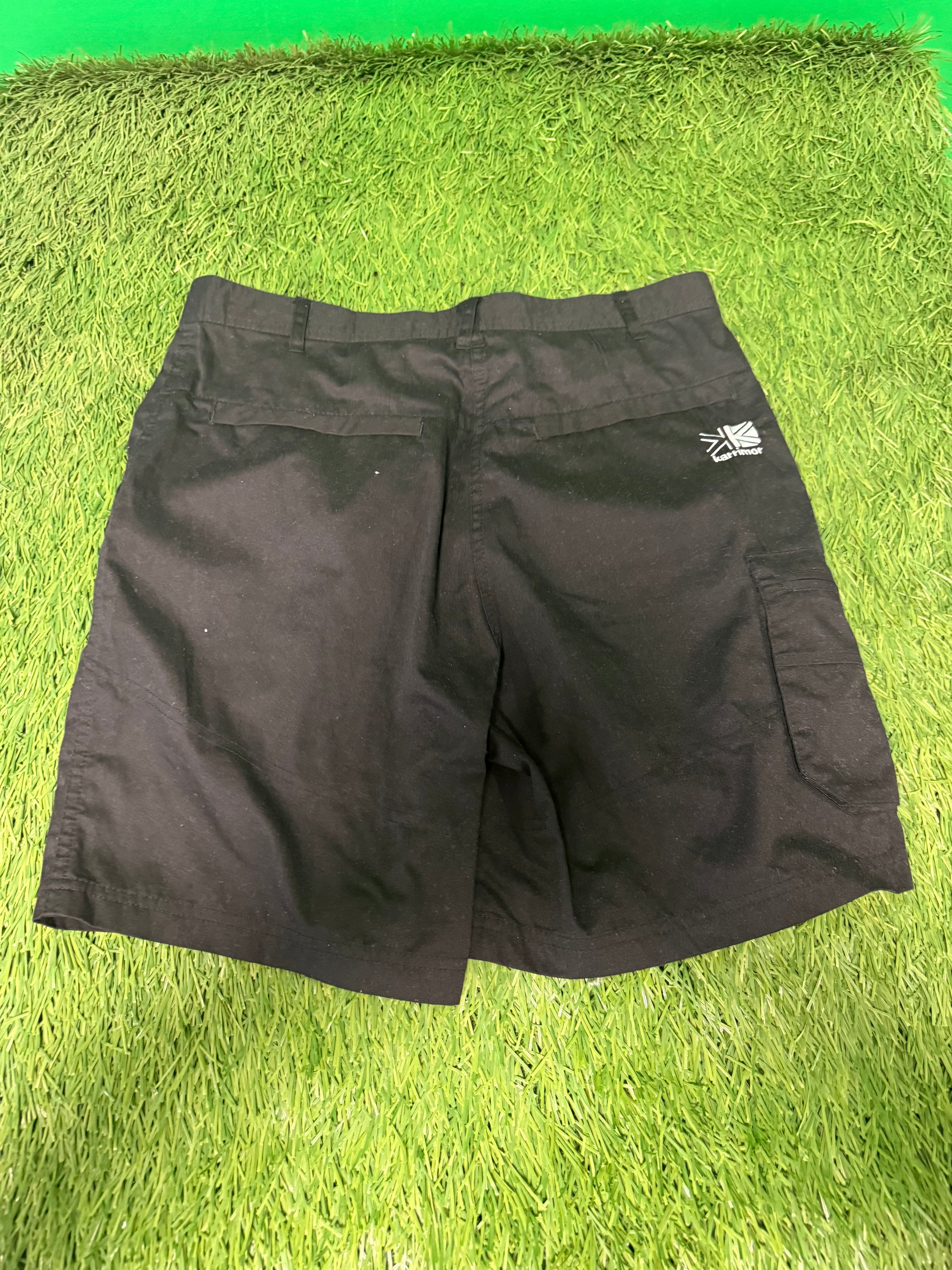 Back view of Karrimor black utility shorts showing Union Jack logo on waistband against green grass