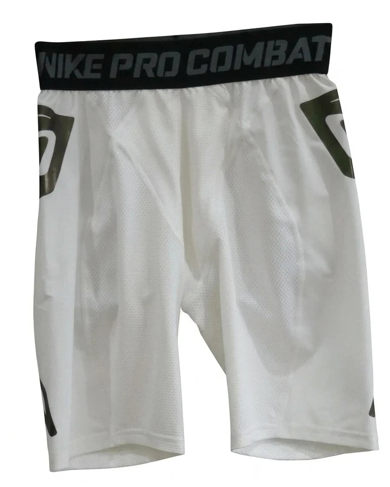 A pair of white Nike Pro Combat shorts for men, featuring a black waistband with repeating grey text, and side mesh panels, is isolated on a pure white background.