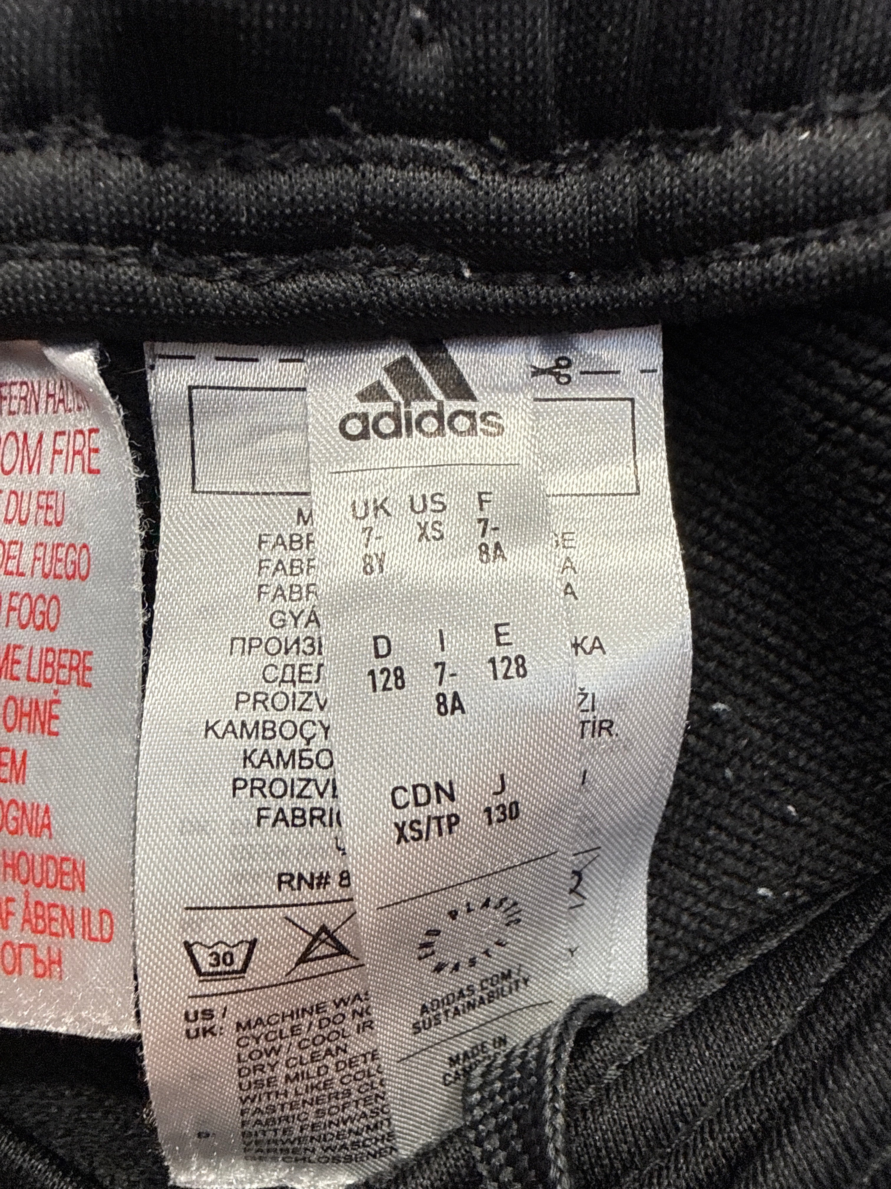 Close-up of adidas label showing size and care instructions on Manchester United kids' training pants
