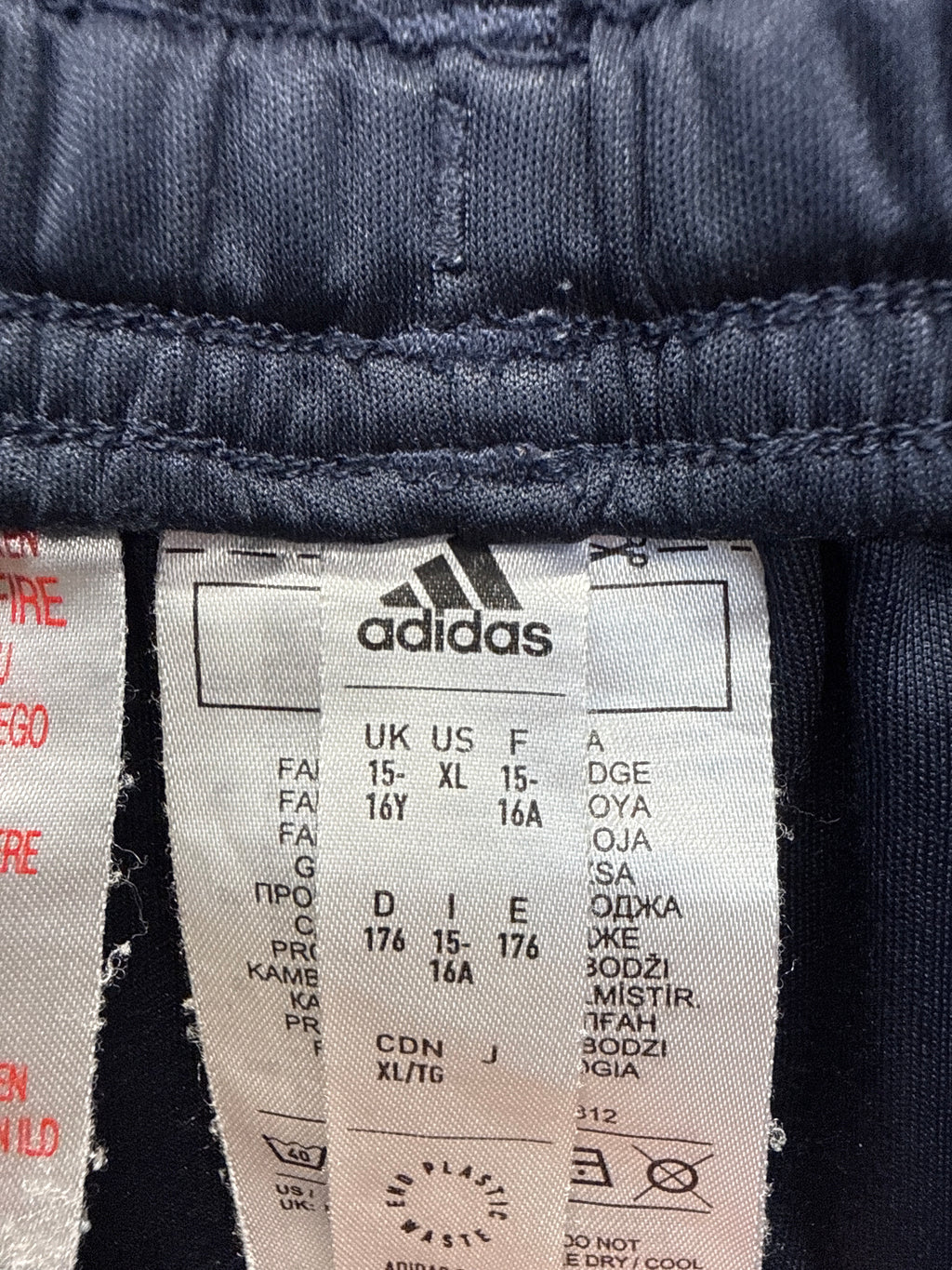 Close-up of adidas size and care label inside youth football shorts