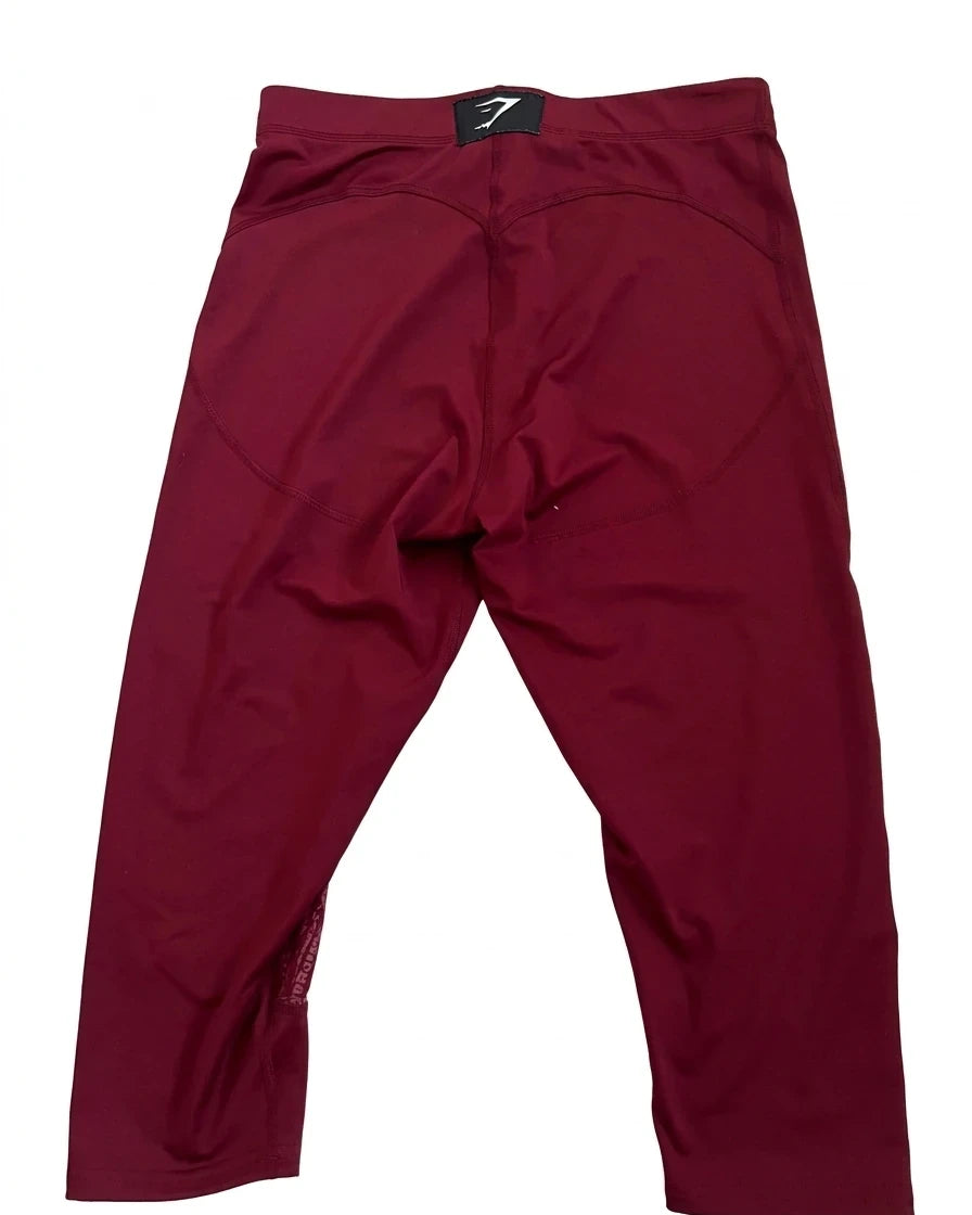 Enhanced Back view of burgundy Gymshark cropped leggings showing logo patch on waistband
