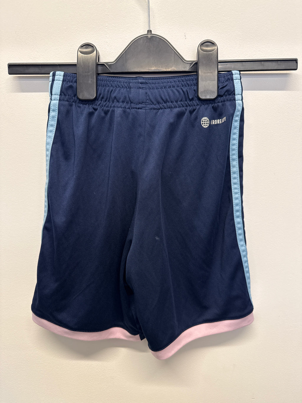 Back view of navy blue Arsenal kids' football shorts showing light blue side stripes and pink hem