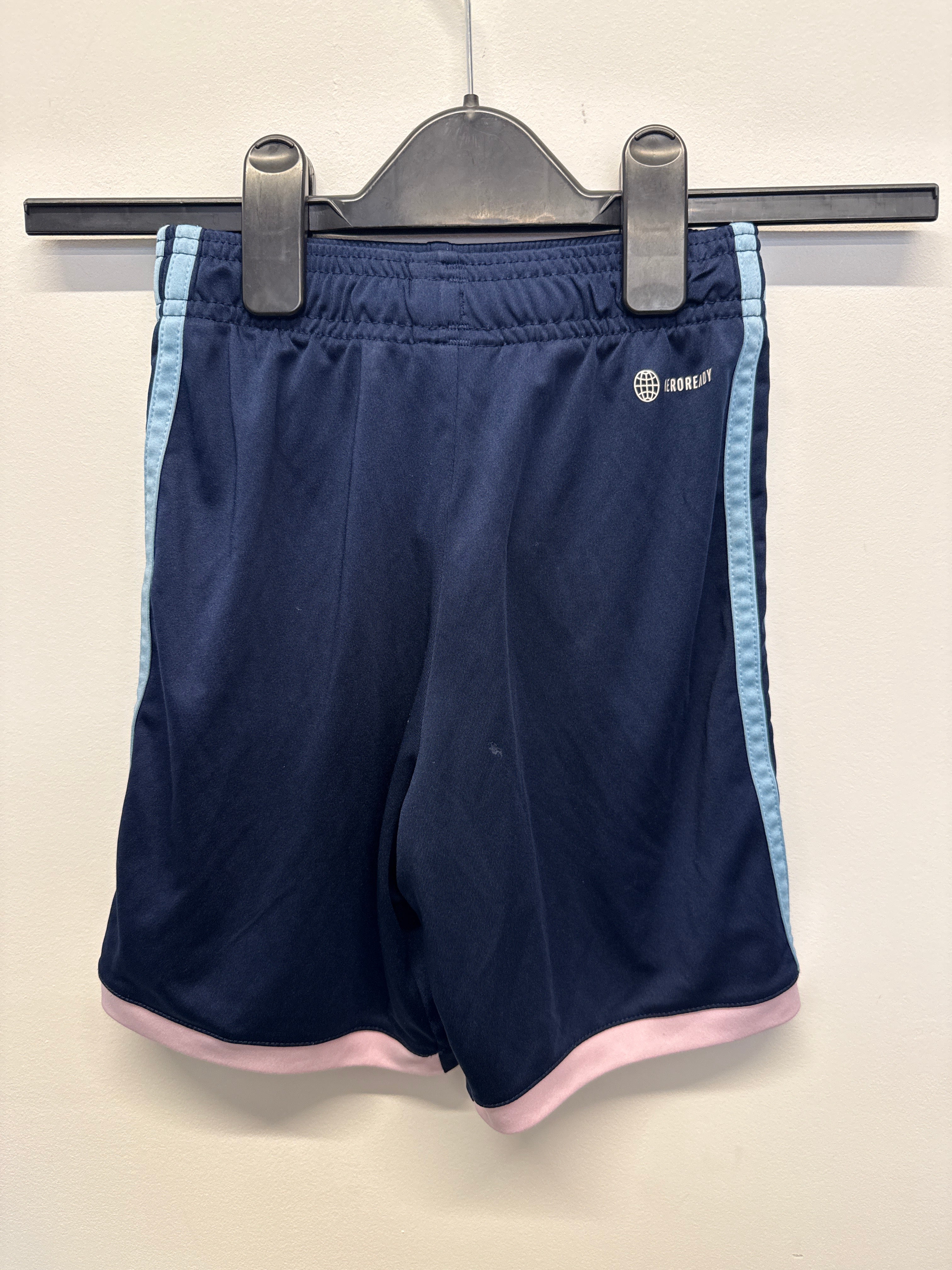 Back view of navy blue Arsenal kids' football shorts showing light blue side stripes and pink hem