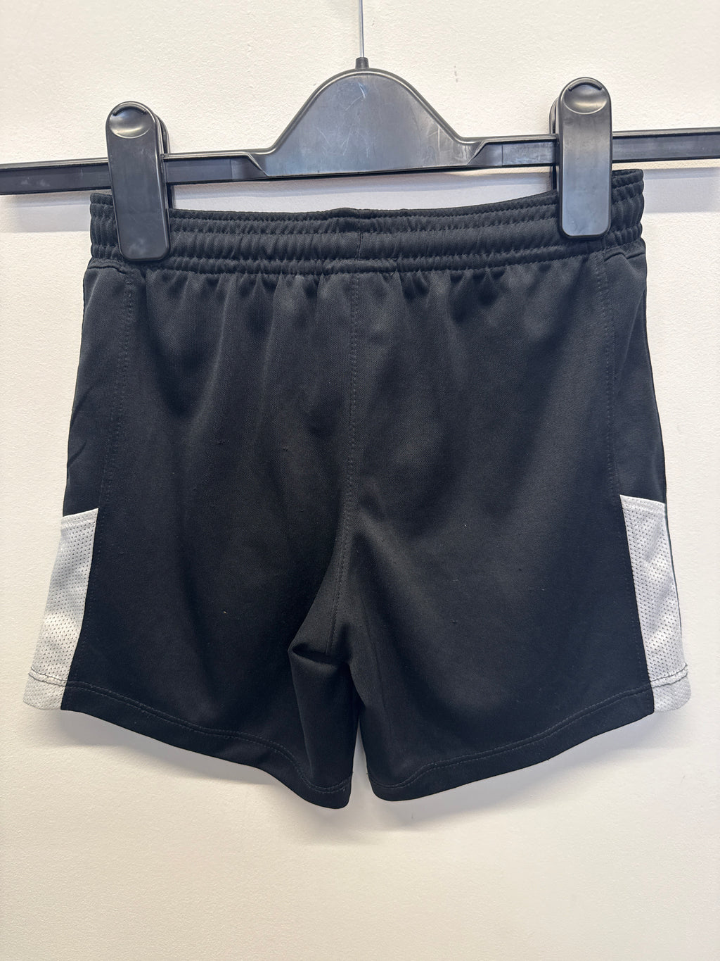 Back view of black Nike football shorts with white mesh side panels
