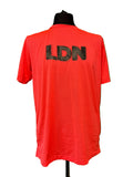 Red sports T-shirt with black LDN lettering on the back displayed on a mannequin against green background