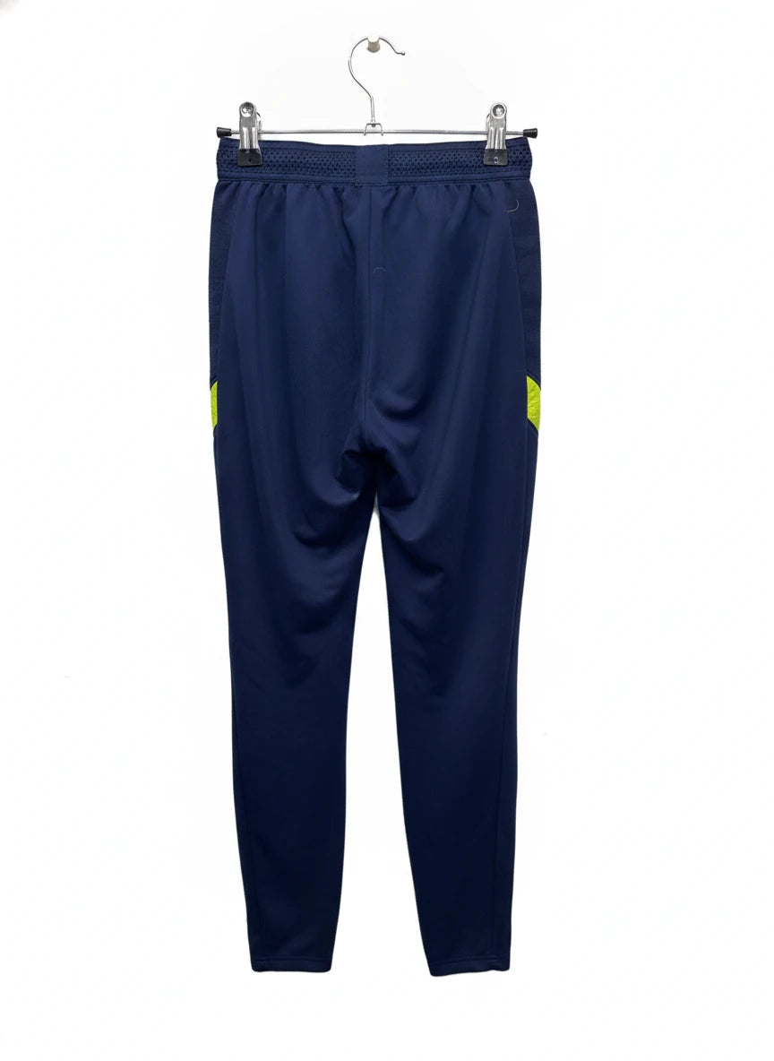 Nike Tottenham Hotspur Dri-FIT Training Pants in navy blue with yellow accents, hanging on a white background.