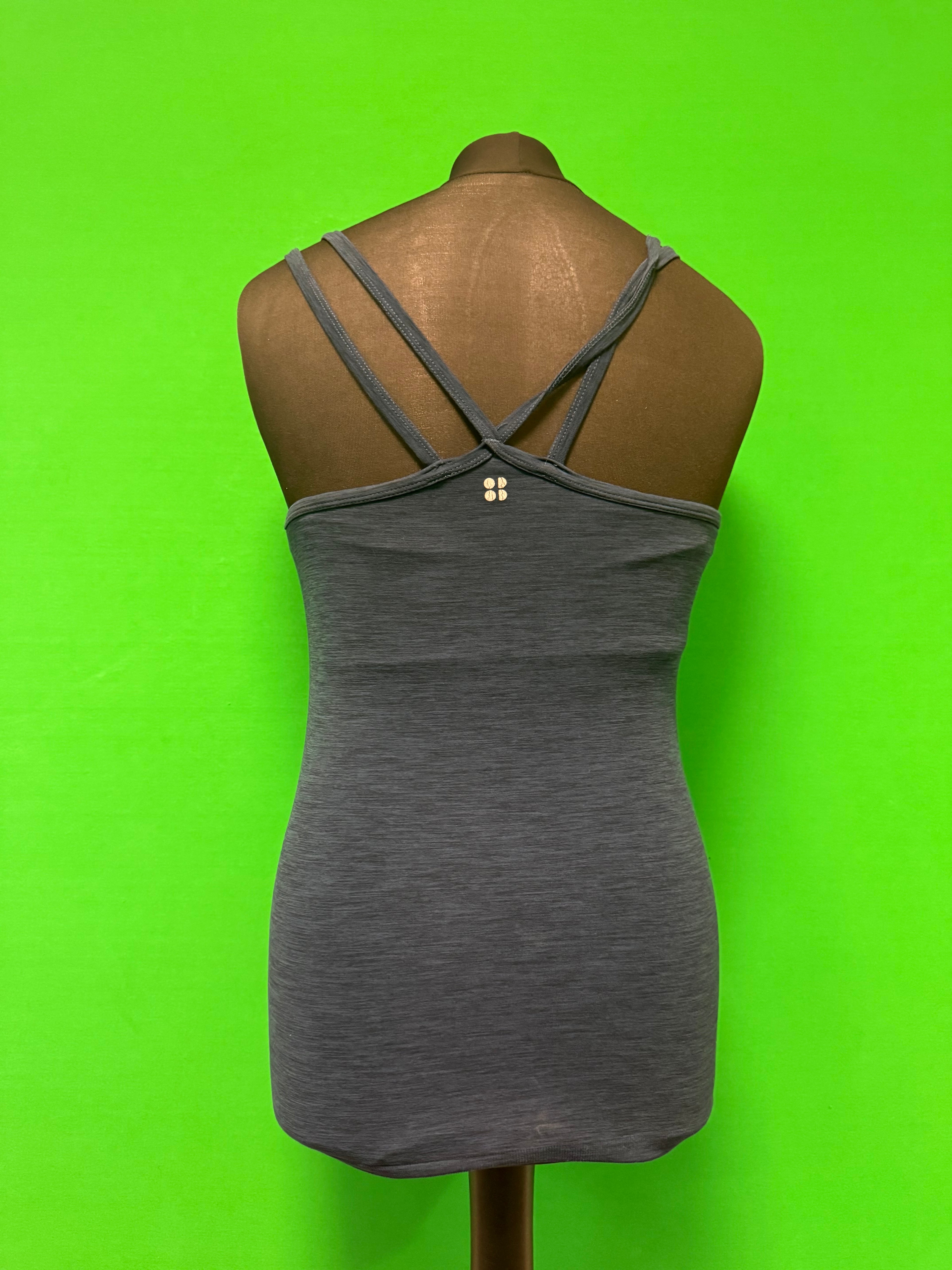 Back view of grey women's activewear tank top with crossed double straps and small logo on mannequin against bright green background