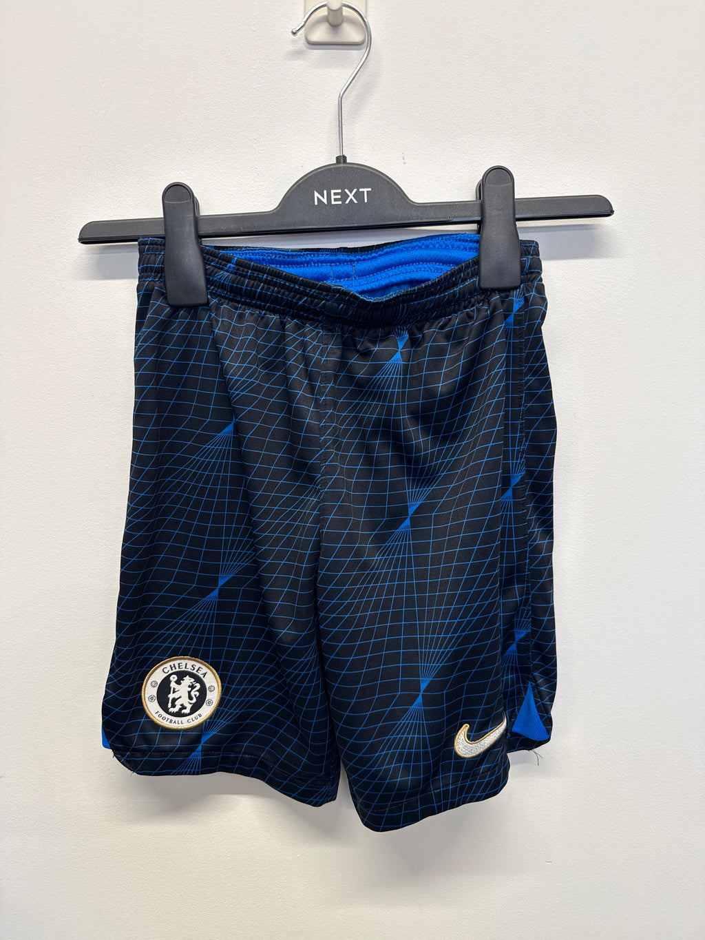 Front view of Nike Chelsea FC kids' Dri-FIT football shorts with blue grid pattern, Chelsea crest, and Nike Swoosh logo