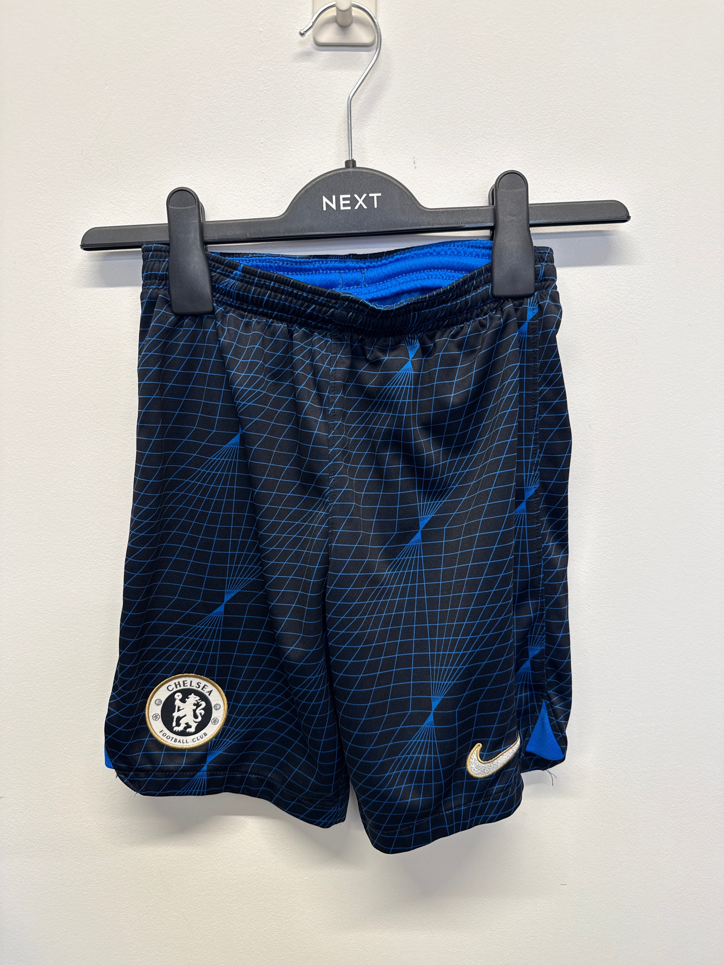Front view of Nike Chelsea FC kids' Dri-FIT football shorts with blue grid pattern, Chelsea crest, and Nike Swoosh logo