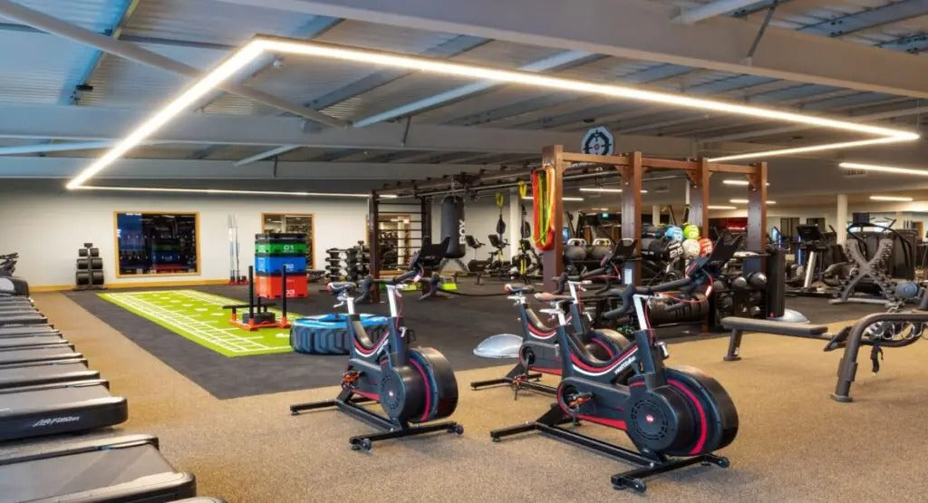 Gym interior with various exercise equipment including treadmills, bikes, and weights.