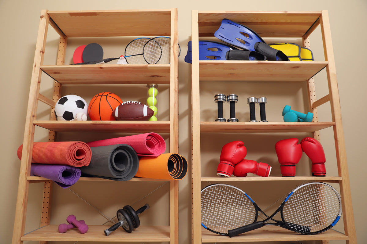 Wooden shelving with multiple items of sports equipment including rackets, weights, boxing gloves, balls and flippers