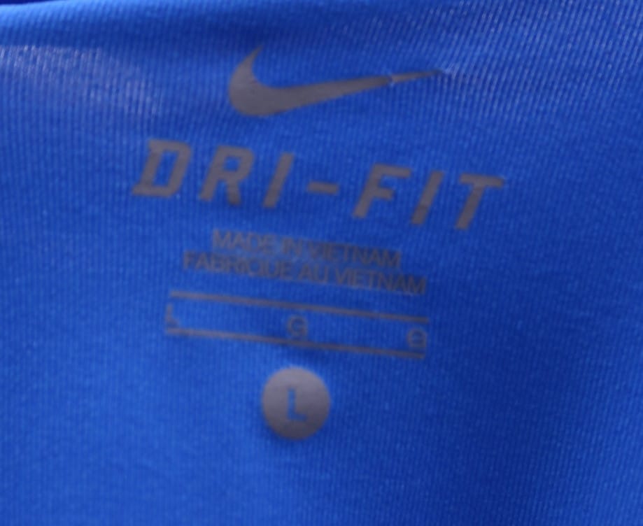 Close-up of Nike Dri-Fit label and size on blue athletic t-shirt