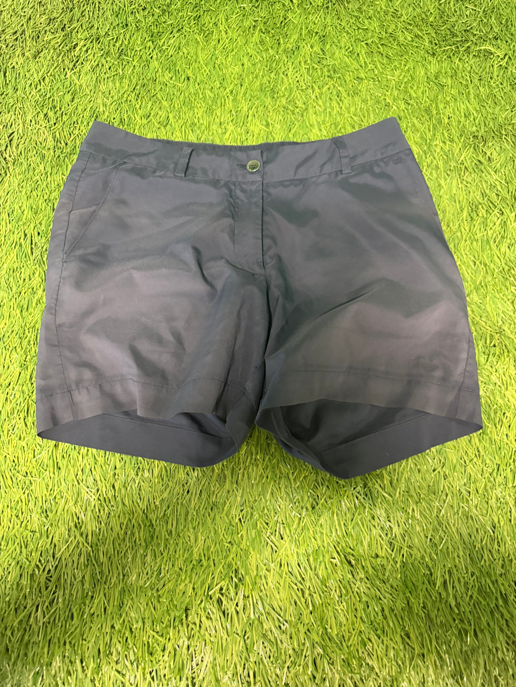 Front view of black Galvin Green golf shorts on green grass