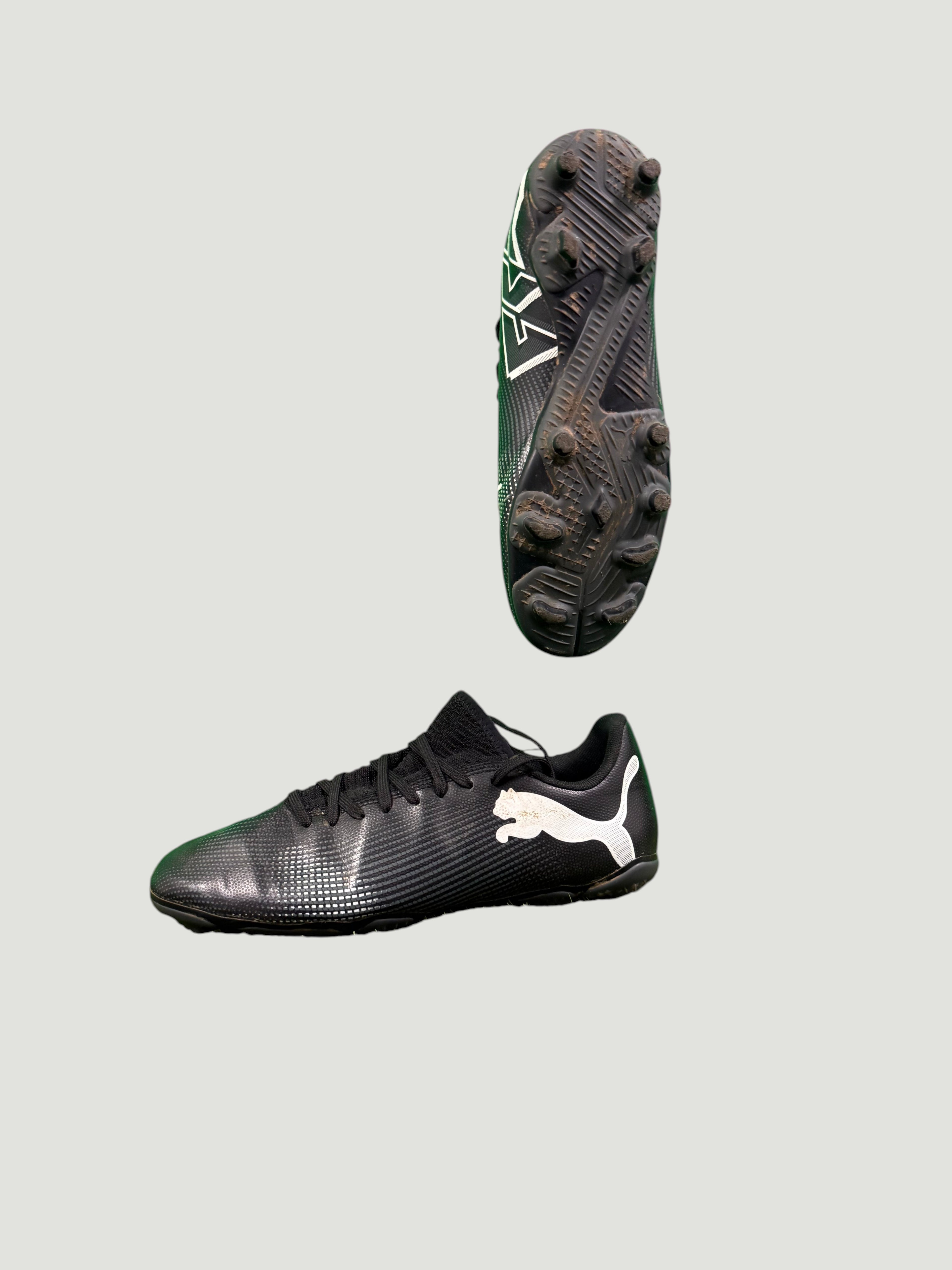 Side view and studded sole of black Puma football boot with white logo