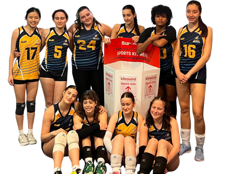 Group of women in sports uniforms posing with a kitround banner.