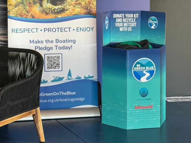 Blue recycling bin with 'Green on the Blue' branding next to a promotional banner.