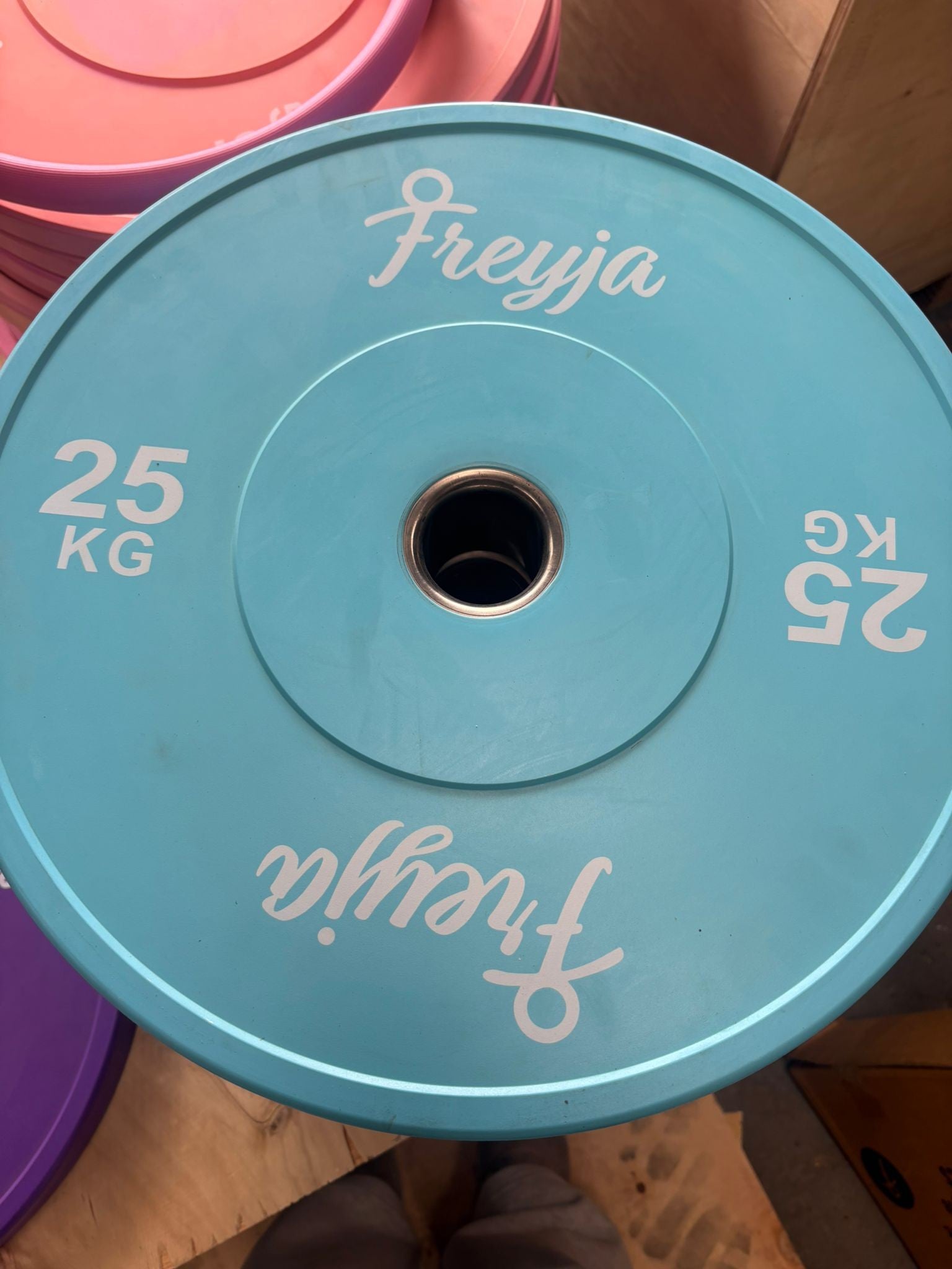 Blue 25kg Freyja bumper plate with white text and steel centre ring