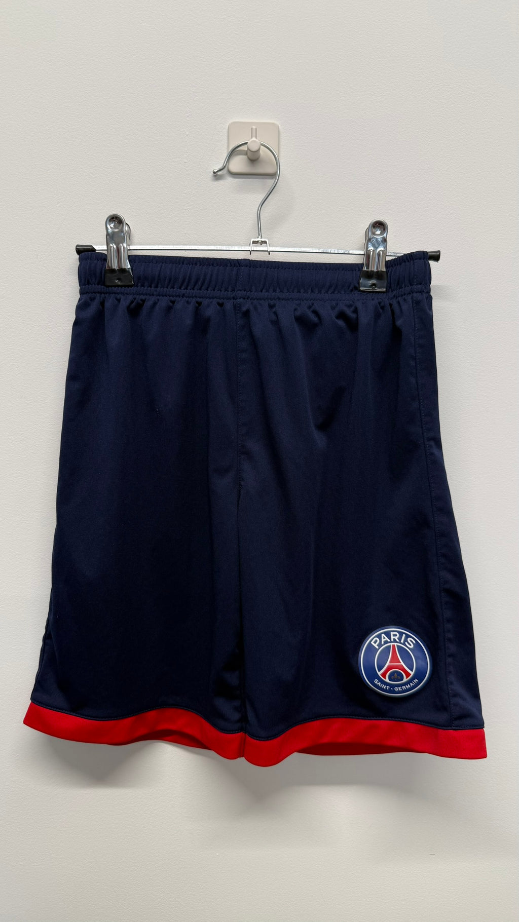 Front view of PSG kids navy shorts with red trim and club badge