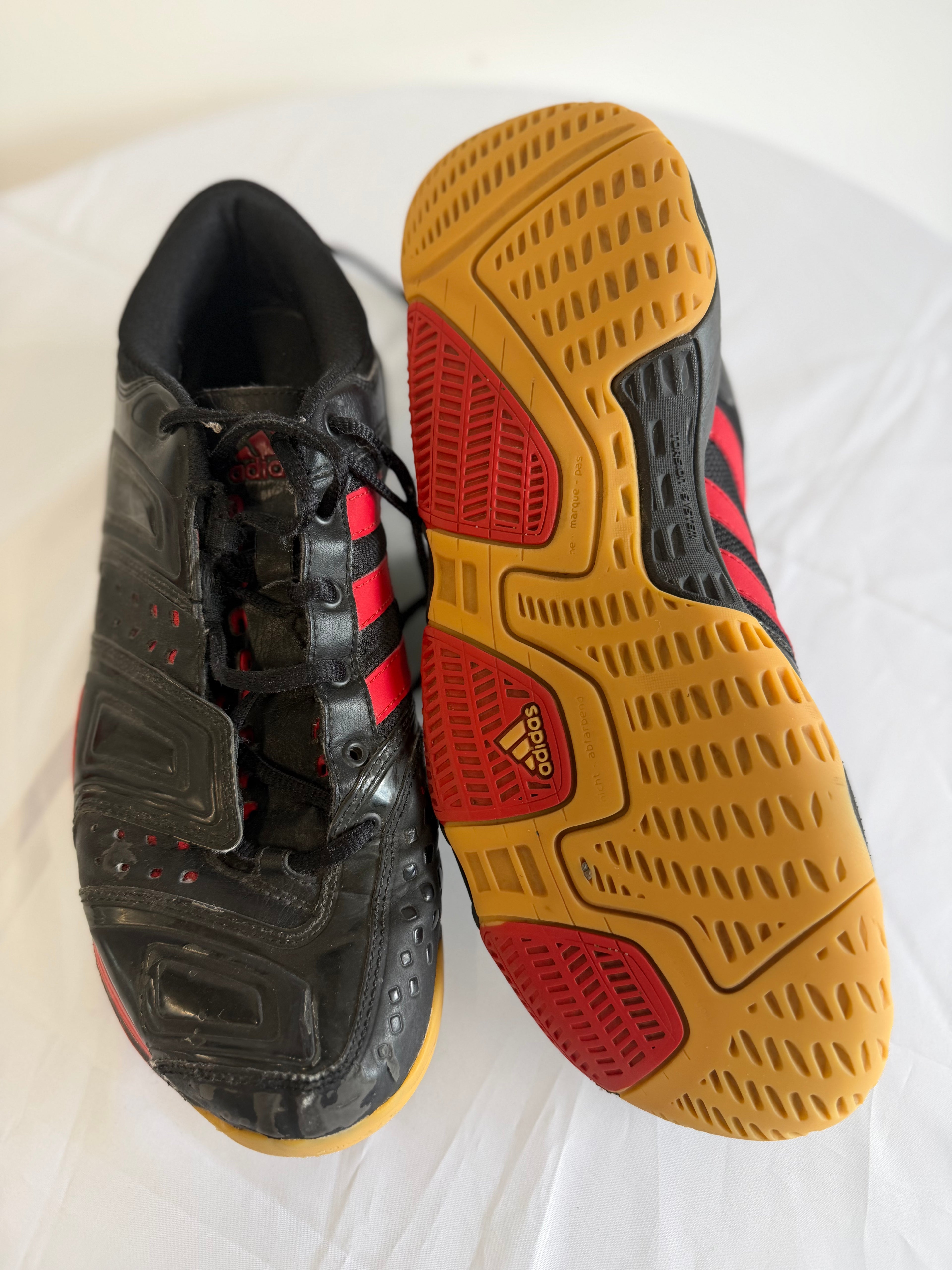 Adidas court shoes with focus on outsoles and red detailing