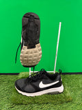 Black and white Nike Air running trainers on artificial grass with one showing the sole tread pattern