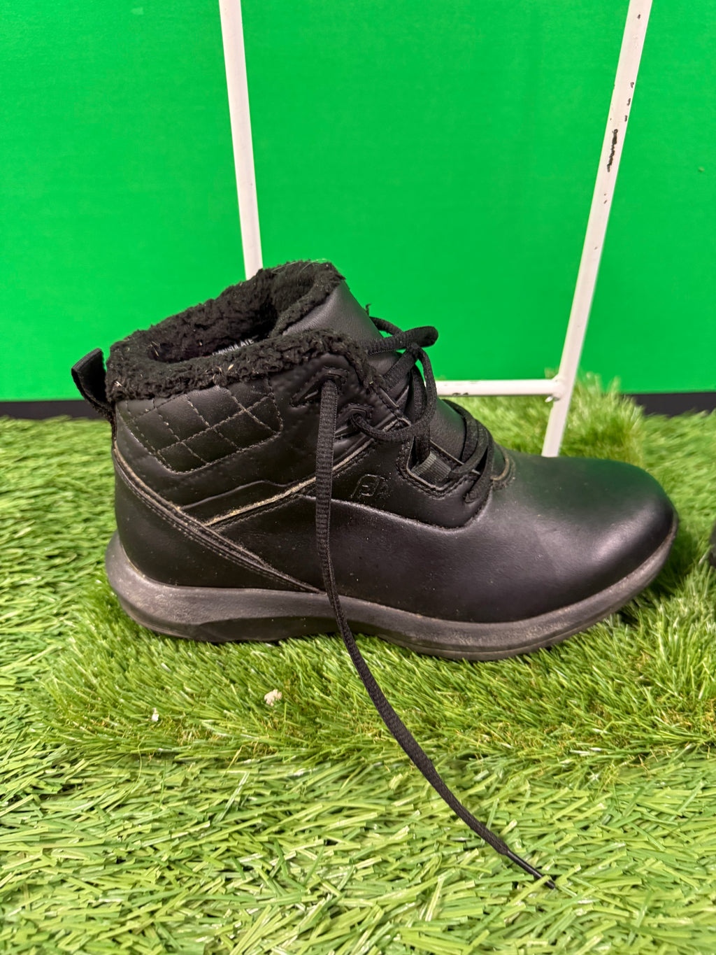 Side view of a single black Footjoy golf boot showing quilted ankle padding and lace-up closure