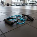 Blue resistance band with black foam handles lying on artificial grass