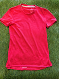 Front view of a bright red Adidas Supernova women's running t-shirt laid flat on green grass showing short sleeves and crew neck