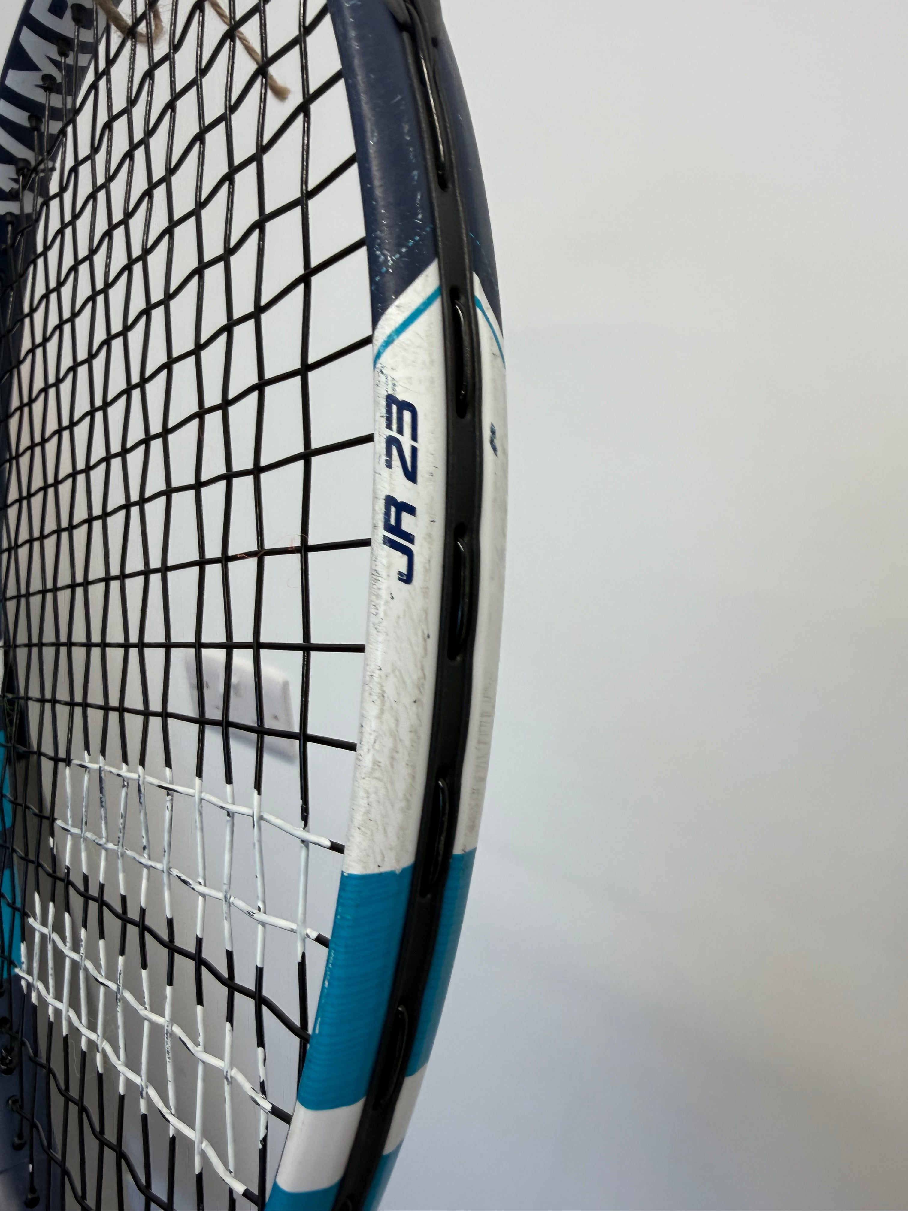Babolat JR 23 marking and black stringing on blue and white tennis racket head