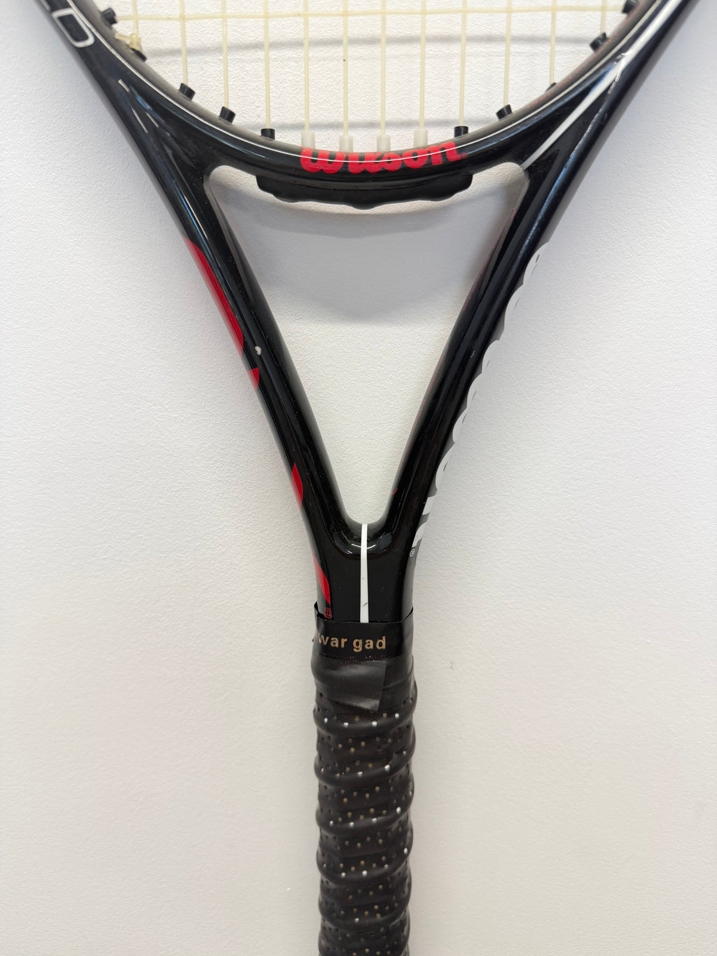 Handle and throat section of Wilson tennis racket with gripped handle against white background