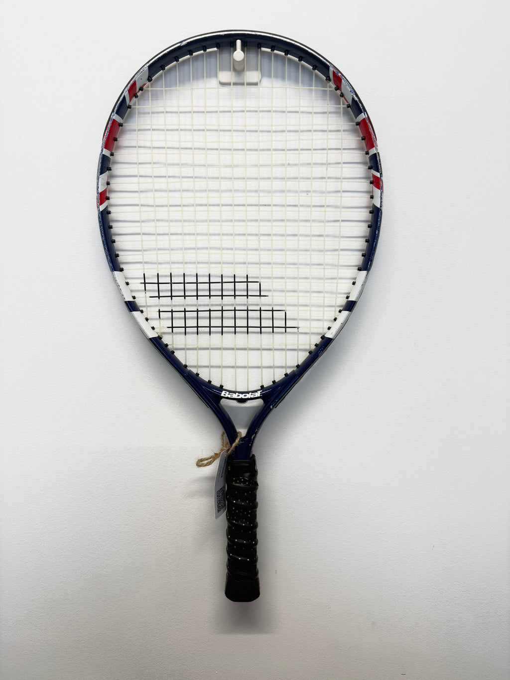 Full-length Babolat blue kids tennis racket hanging on wall