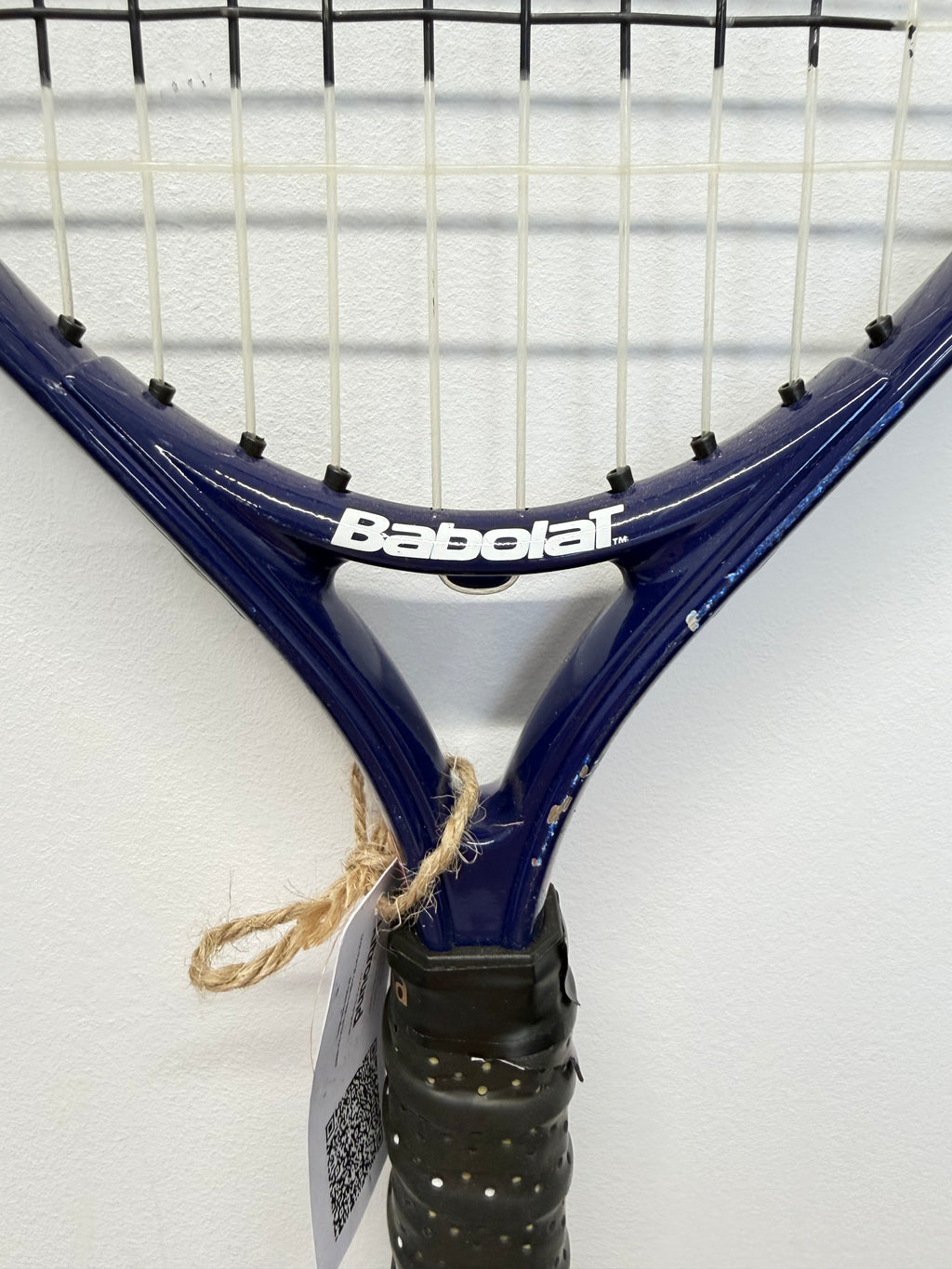 Detailed view of Babolat logo and stringing on blue kids tennis racket
