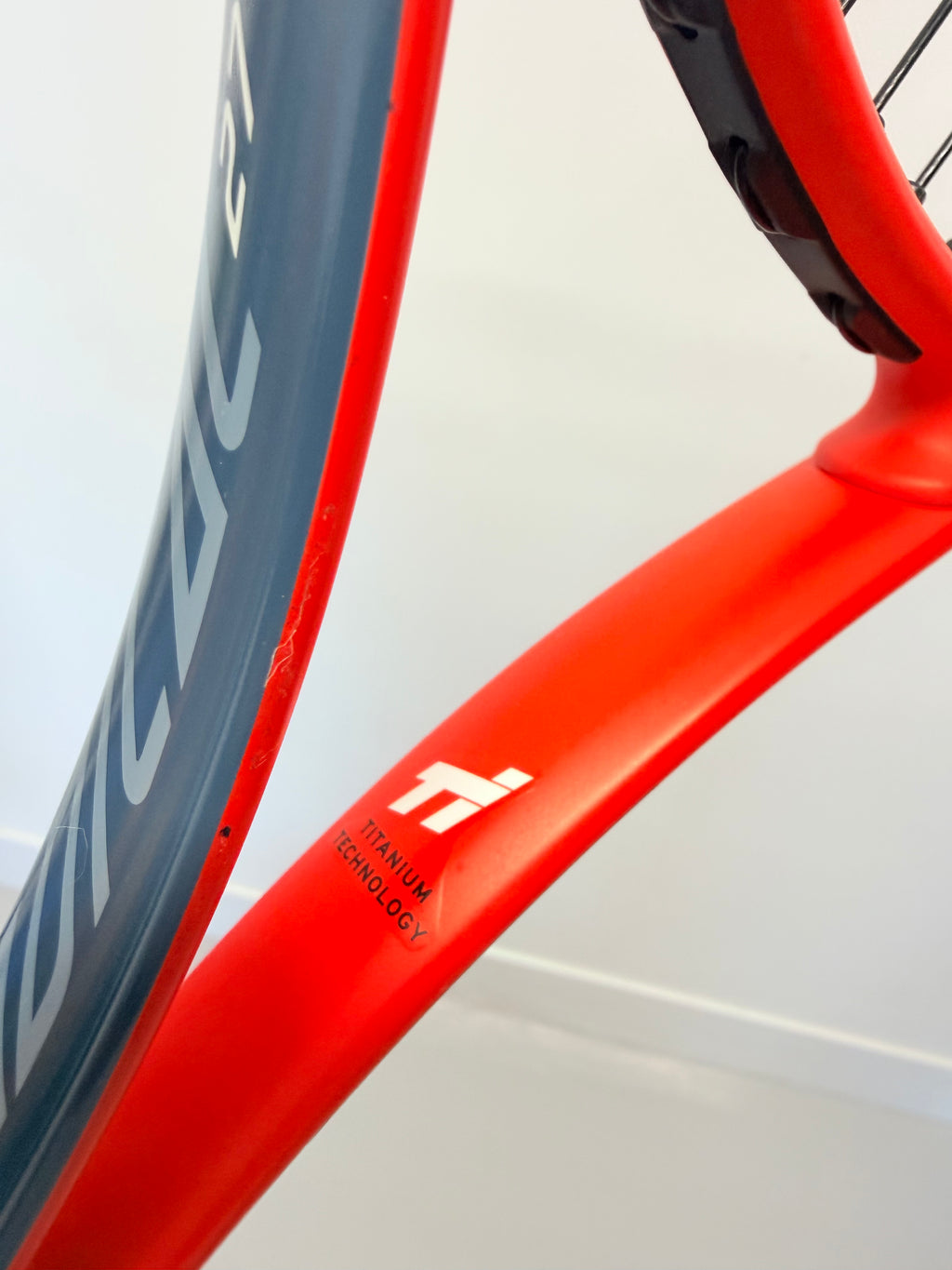 Close-up of Head Radical 27 tennis racket showing titanium technology logo on red frame