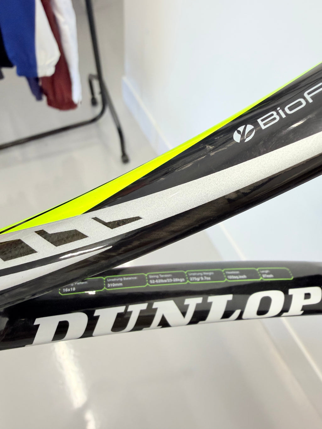 Close-up of Dunlop racket showing branding, string pattern, and specifications