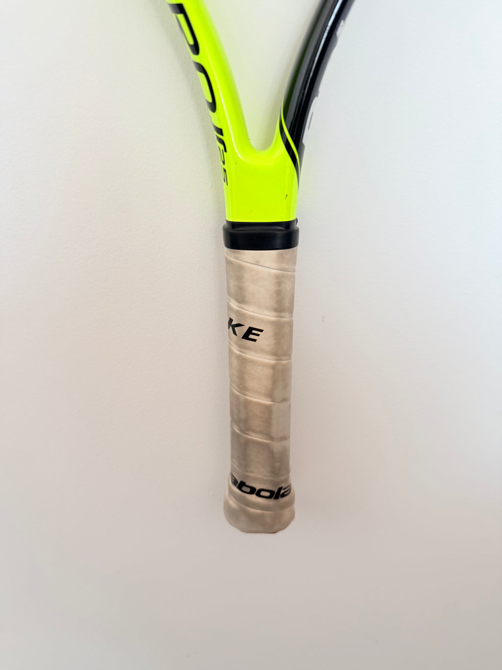 Tennis racket handle with grip tape and partial Babolat branding visible