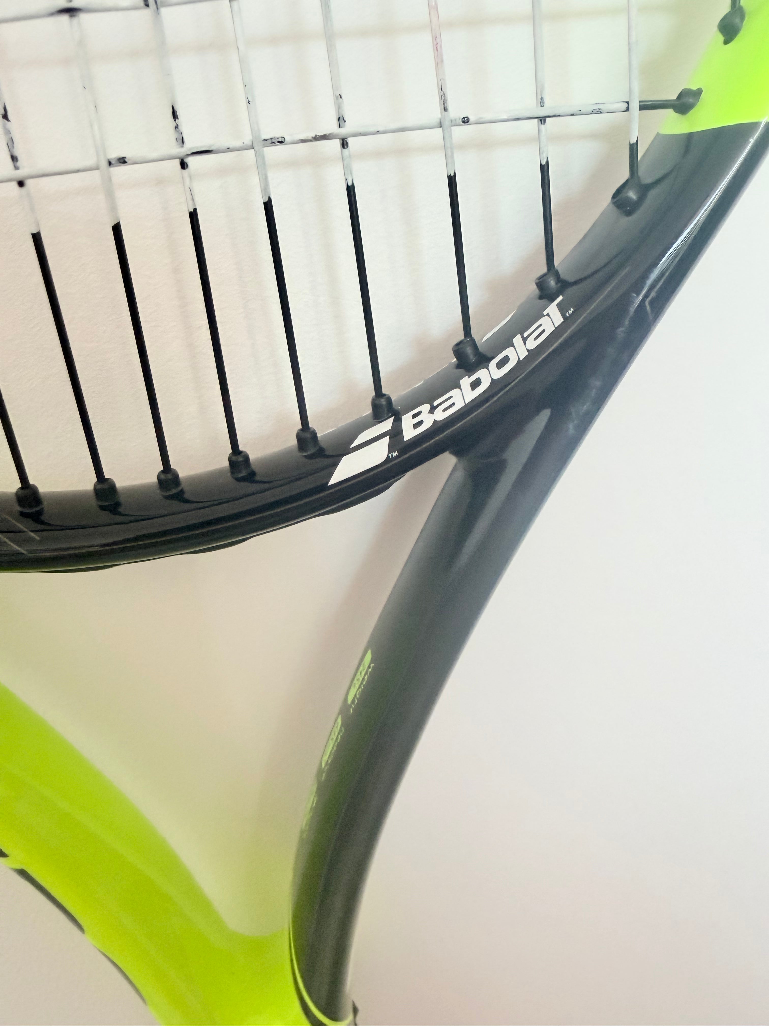 Close-up showing Babolat logo and racket strings on yellow and black frame