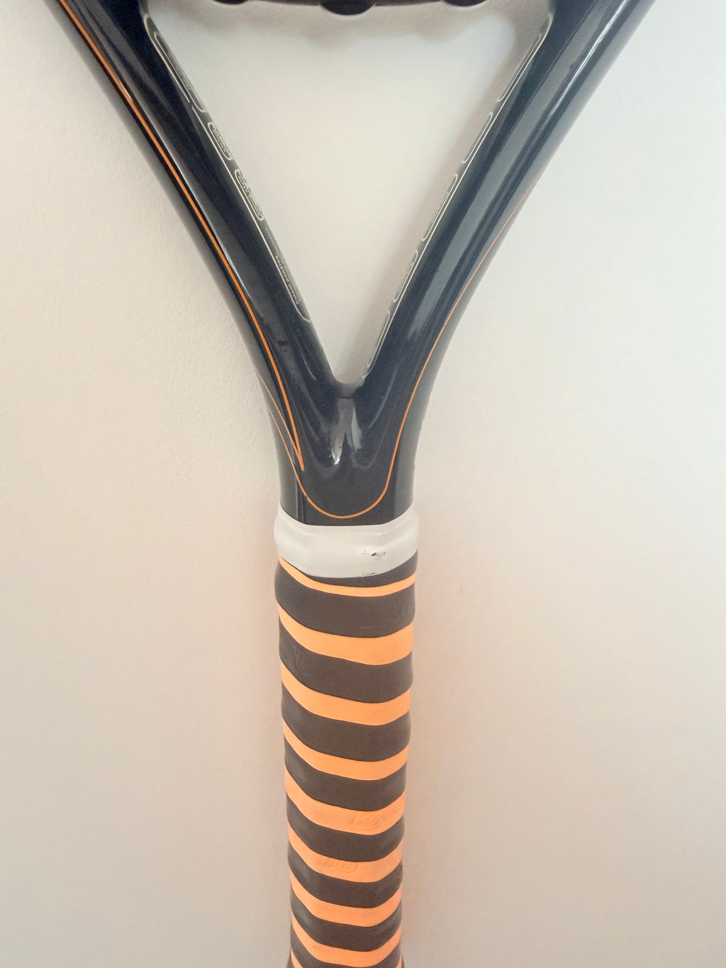 Handle and throat of black and orange Head tennis racket