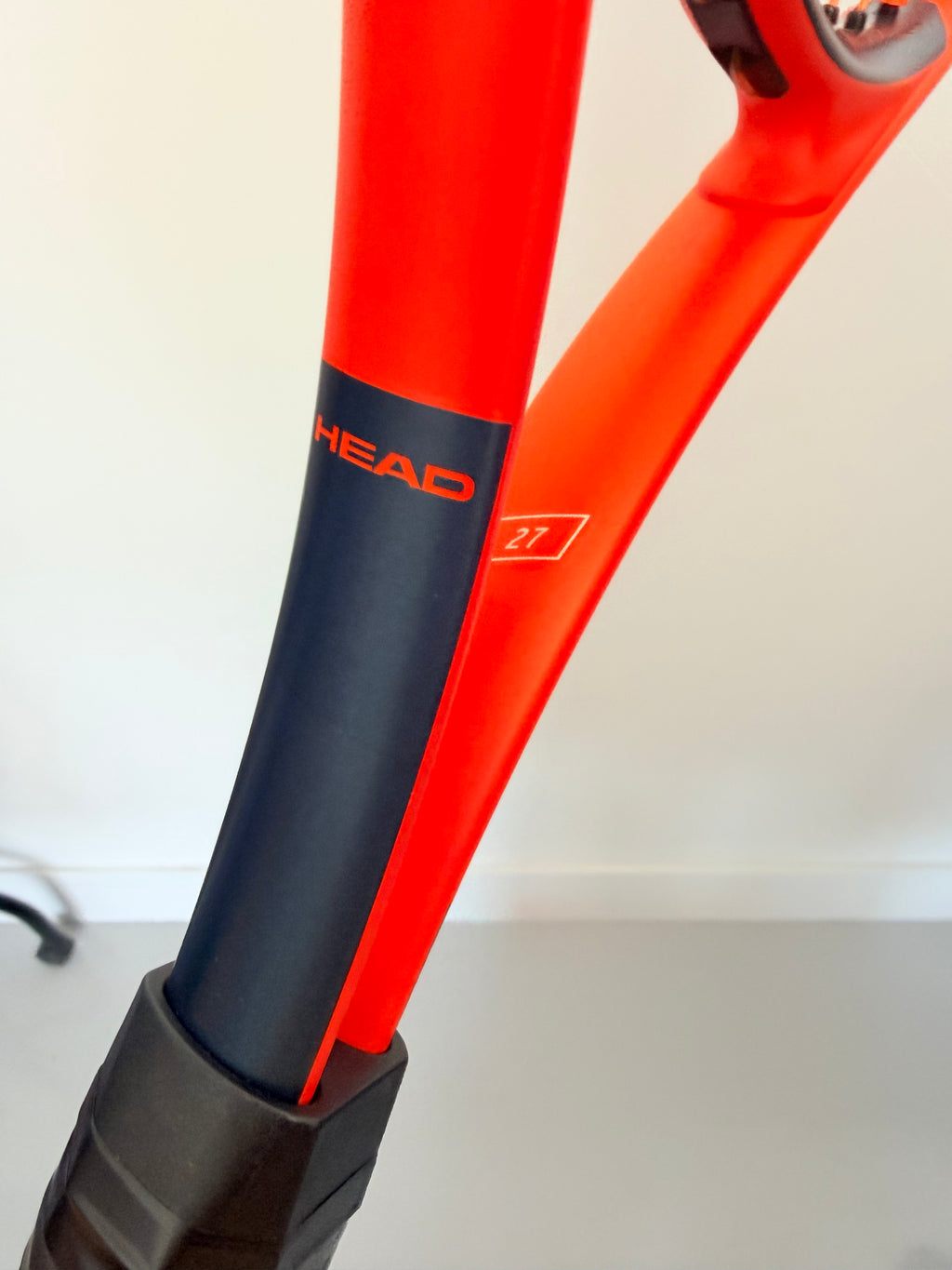 Close-up of Head branding on orange and black tennis racket
