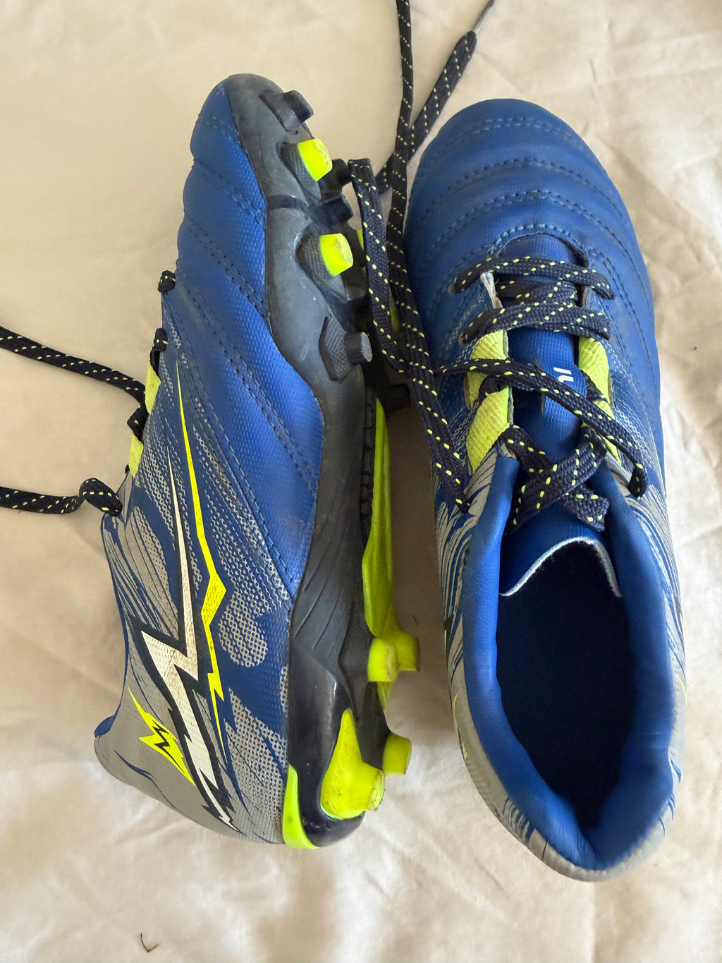 Angled view of blue and grey Kipsta football boots with lace detail and sole