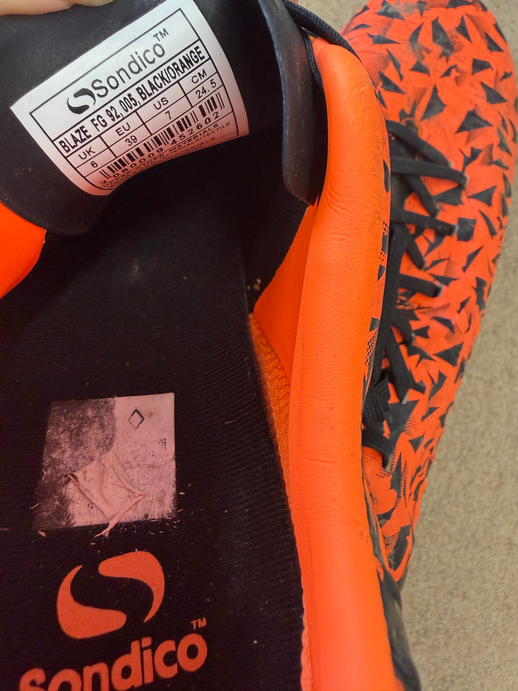 Internal label of Sondico Blaze football boots indicating size and black/orange colourway